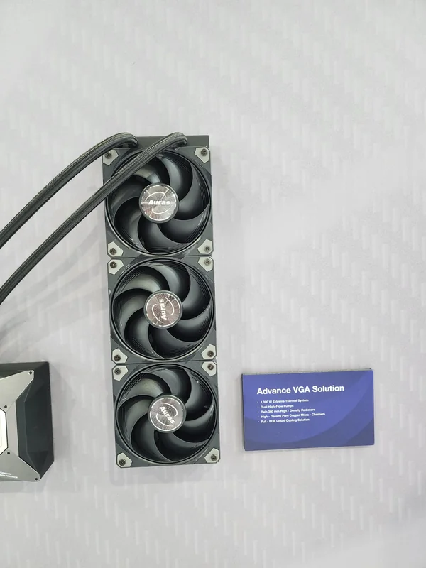 A vertical array of three black fans with Auras branding next to a sign titled 'Advance VGA Solution' listing features like a 1,000W extreme thermal system and dual Hi-Flow pump.