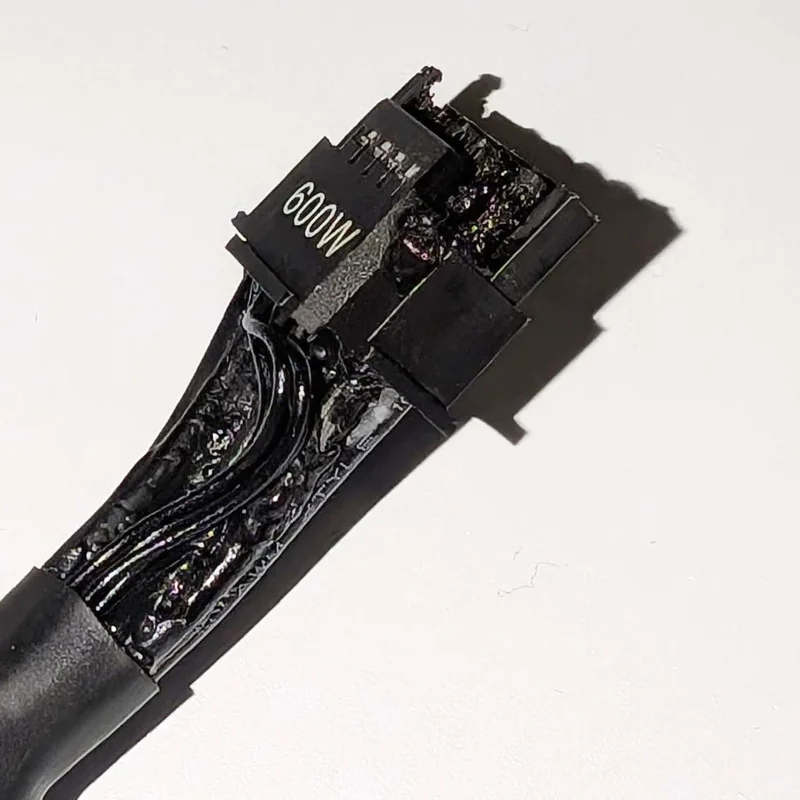 A close-up of a damaged power connector labeled '600W' with melted wiring.