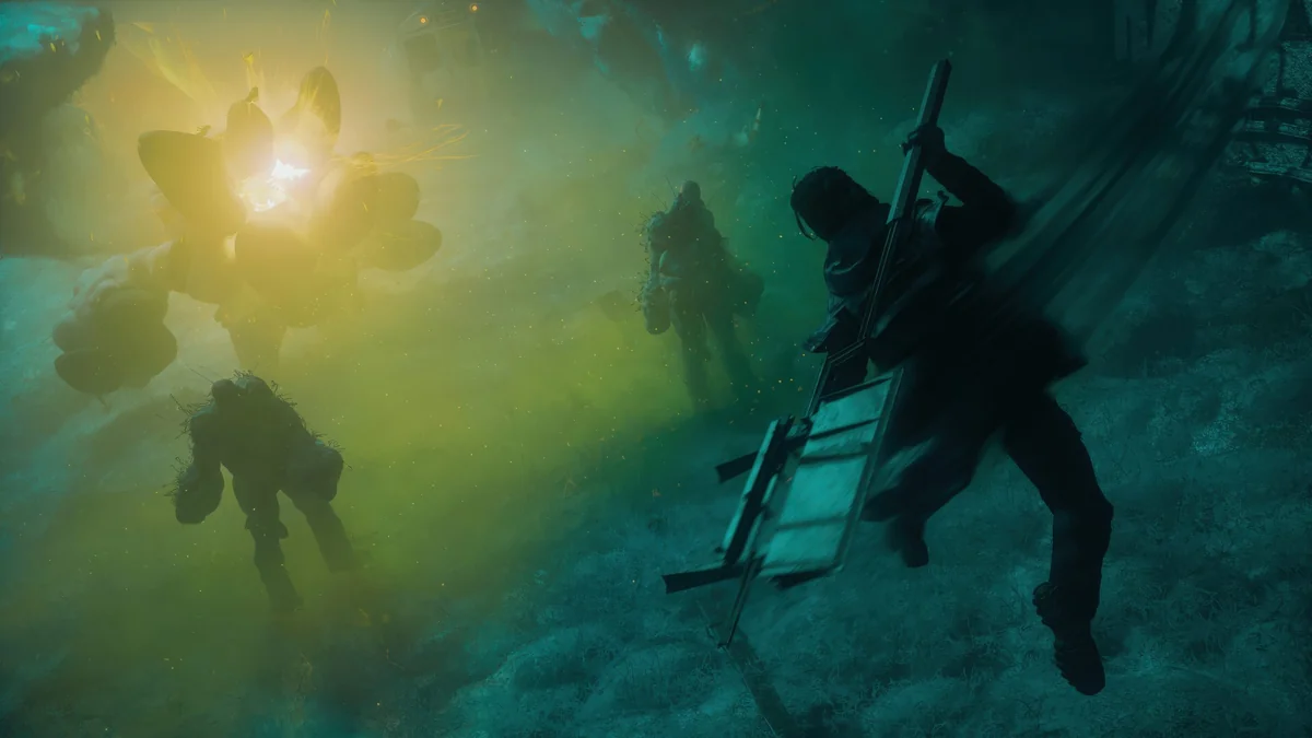 Characters in combat in a foggy, alien landscape are illuminated by a glowing explosion in a scene from the game Returnal.