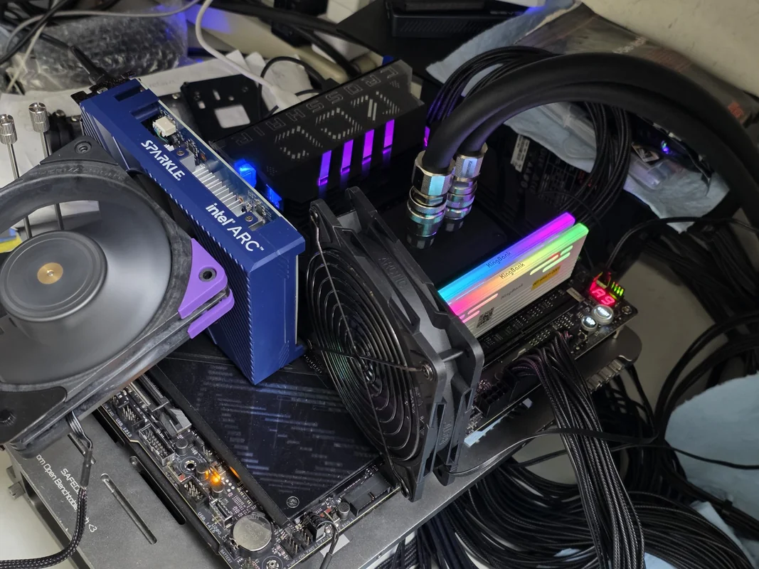 A PC setup features a Sparkle Intel Arc graphics card with a fan, RGB-lit RAM sticks labeled with 'Neo Forza,' and liquid cooling tubes connected to the CPU on an open test bench.
