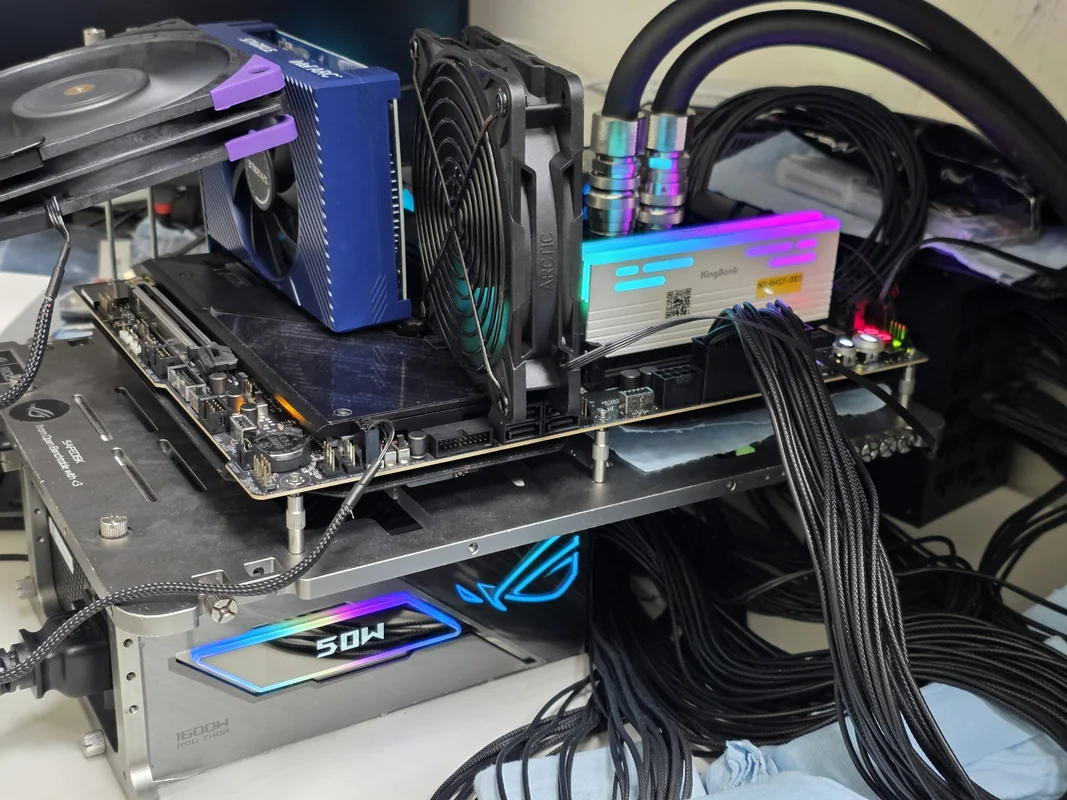 A PC open test bench setup features an ASUS ROG STRIX motherboard, an Intel Arc graphics card, a KingBank DDR5 memory module, and an ASUS ROG THOR 1600W power supply.