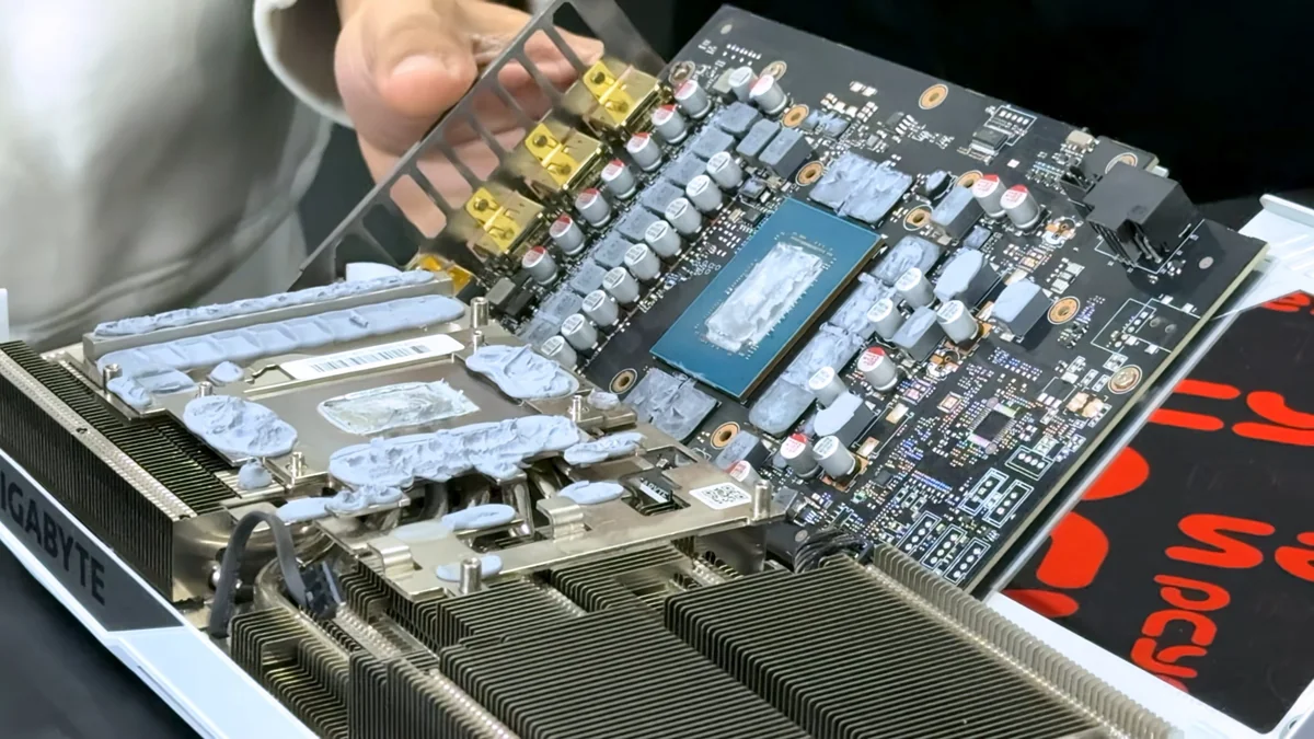 A Gigabyte graphics card is shown with its heatsink removed, revealing the exposed GPU chip and circuitry.