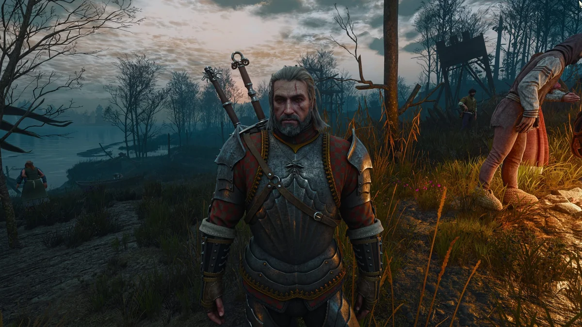 Geralt of Rivia, in armor, stands near a campfire in a marshland setting at dusk in 'The Witcher 3: Wild Hunt'.