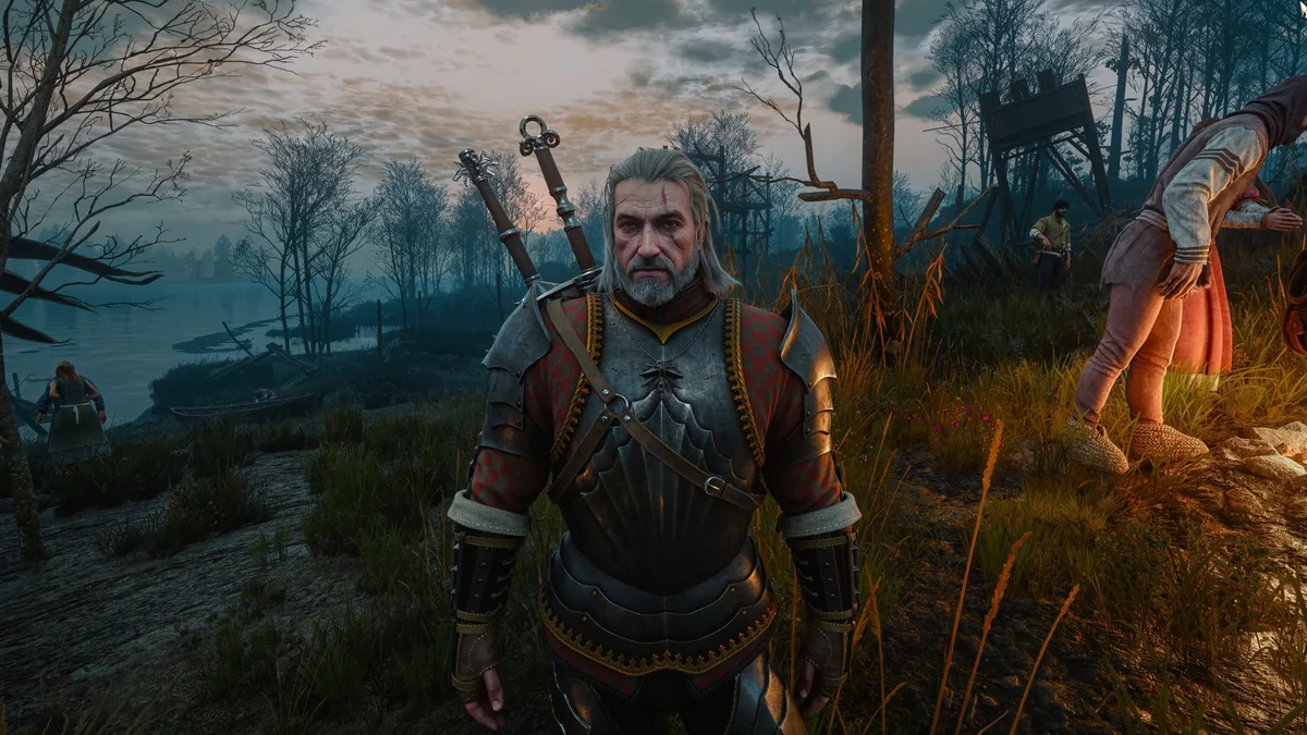 Geralt of Rivia from The Witcher 3: Wild Hunt standing in armor by a lakeside with villagers in the background.