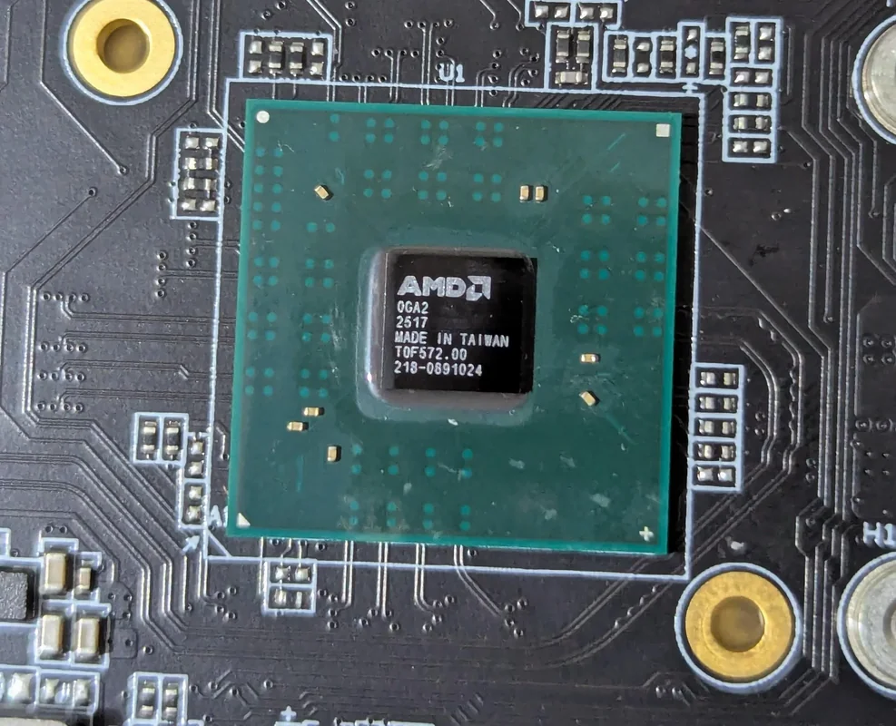 A close-up of an AMD chip labeled 'OGA2 2517 MADE IN TAIWAN TOF572.00 218-0891024' mounted on a circuit board.