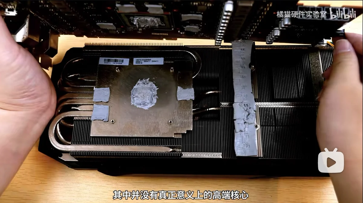 A person is disassembling a graphics card with visible thermal paste residue on the heatsink.